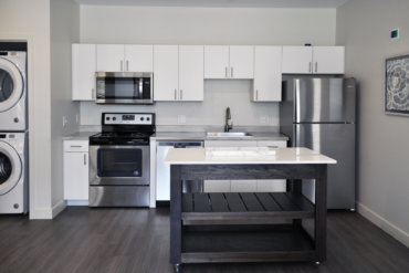 Bright kitchen in apartment 2-F with neutral laminate countertops, a moveable island, and stainless steel appliances.