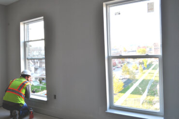 A construction worker enjoys the view of S. Union St. from the bedroom window of a two-bedroom apartment (2-A) in Building D.
