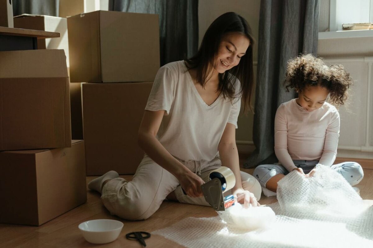 Woman and young girl using bubble wrap to pack for a move