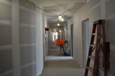 On the 4th floor of Building A, a worker muds drywall.
