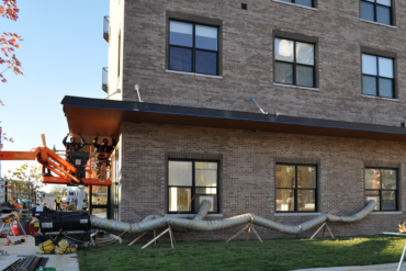 Workers install the facia along what will be the VIDA leasing office in Building B.