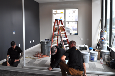 Workers install office enclosures in the new VIDA leasing office in Building B.