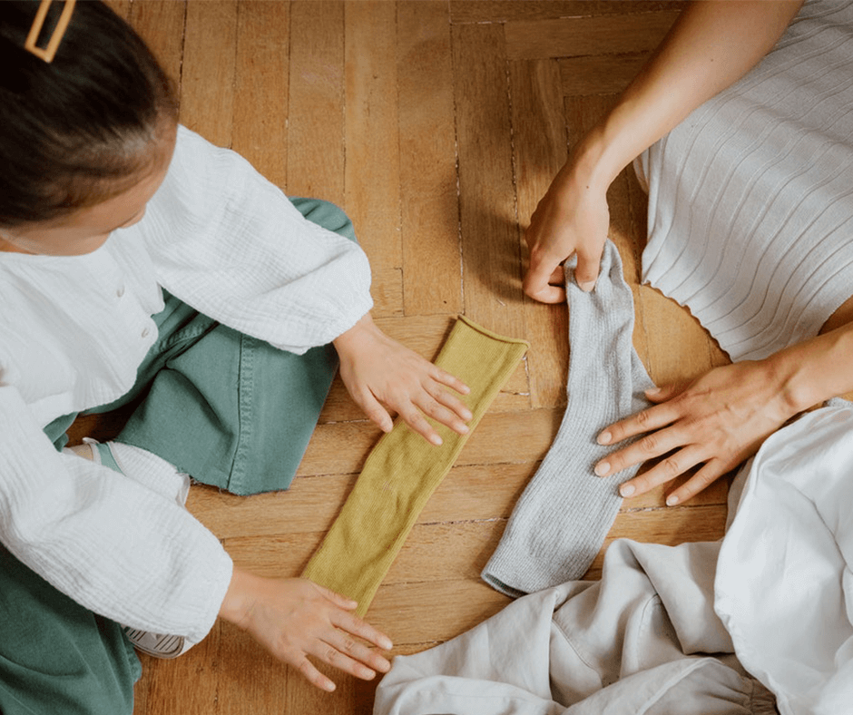 Mother and daughter sitting on the floor folding socks. Image credit: Ron Lach