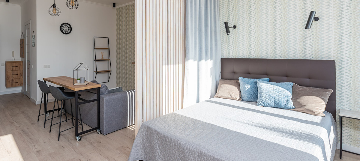 Studio apartment sleeping and television area separated by hanging curtains. Image credit: Max Vakhtbovych