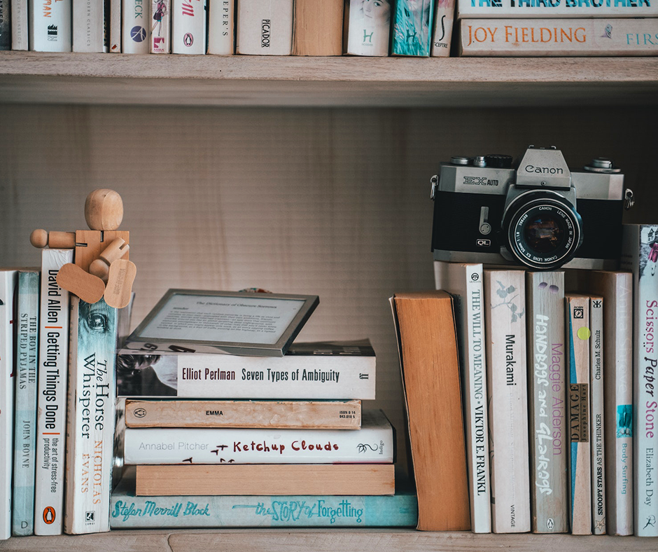 Bookshelf with a vintage 35mm camera and a small wooden figurine. Image credit: Taryn Elliott.
