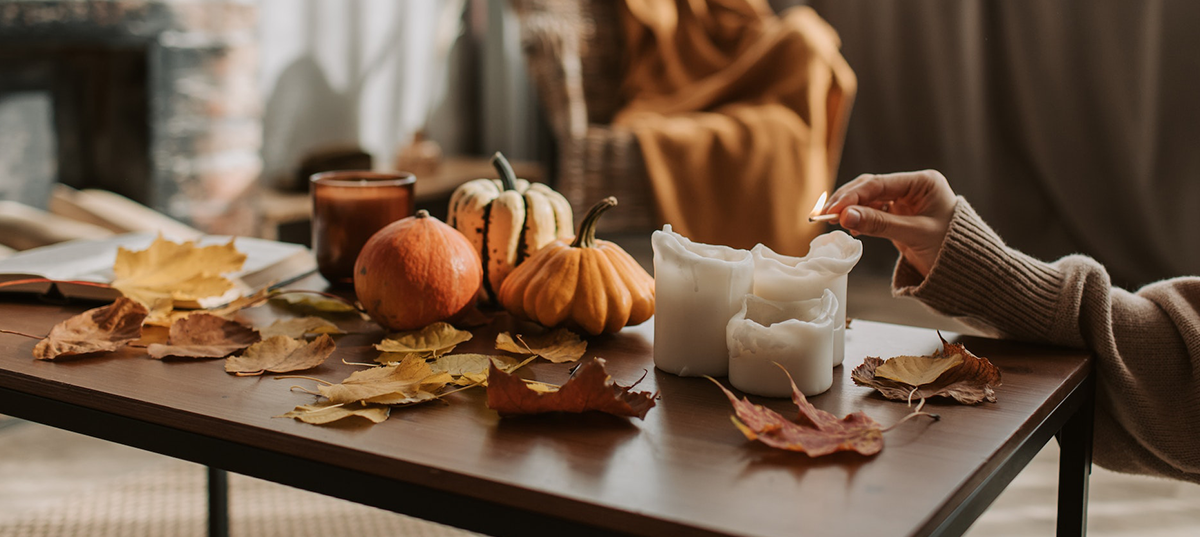 Pumpkins, fall leaves, and candles on a coffee table. Image credit: Vlada Karpovich
