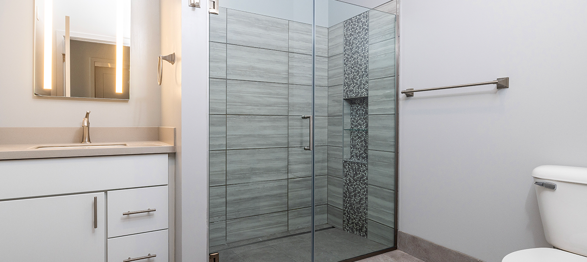 Tile shower with glass doors in apartment 2E at VIDA
