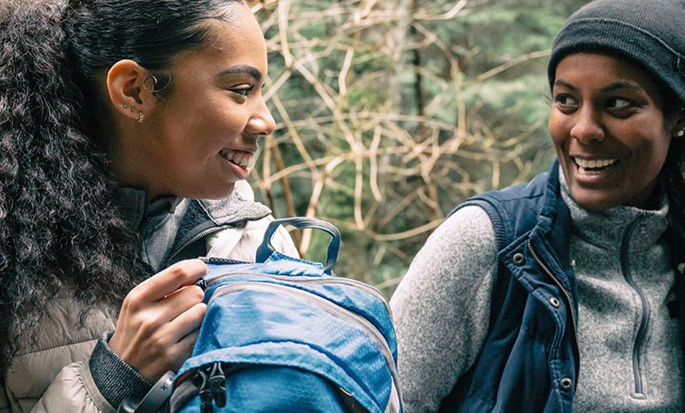 Two women holding a backpack