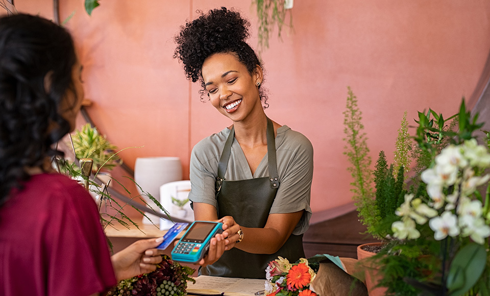 Woman using credit card at flower shop